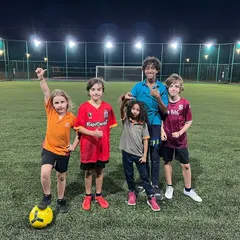 Our academy is a welcoming place for everyone, including expat families looking to connect. This group of players from different backgrounds celebrates after a great training session, showcasing the friendships built on the football pitch.