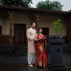 A couple performing a traditional ritual with a tulsi plant in the courtyard of a wada, beautifully capturing a moment of cultural significance.