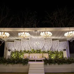 A stage that is both lit and lush. We designed this reception stage with a custom-monogrammed backdrop, flanked by walls of greenery and topped with elegant chandeliers for a fresh yet grand look.