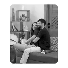 A sweet, candid black and white shot of a couple cuddling on a sofa, capturing a simple, everyday moment of love during their indoor shoot.