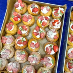A mix of strawberry cream and raspberry crumble mini bombolinis, dusted with powdered sugar.