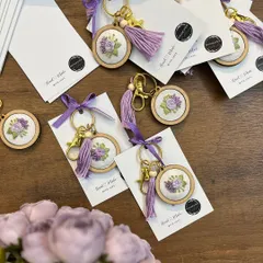 A close-up of the handmade embroidered keychains that were part of the baby announcement gift set. These delicate, personalized favors are a beautiful keepsake for friends and family.