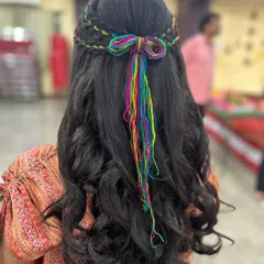 A fun and colorful hairstyle for a Mehendi ceremony. I wove multi-colored threads into her hair to create this unique and festive look that matched her vibrant outfit.