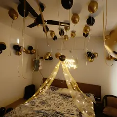 Another view of the romantic birthday room setup, focusing on the fairy light canopy over the bed and the 'Happy Birthday' neon sign.