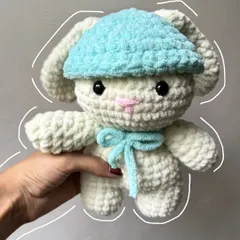 A super soft and cuddly crochet bunny plushie with a cute blue hat and bow, ready for hugs.