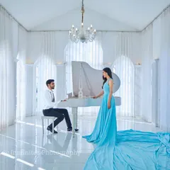 Our all-white studio, complete with a grand piano, provides a backdrop for timeless elegance. The flowing trail of this light blue gown adds a touch of drama and sophistication to this classic couple portrait.