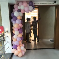 A partial balloon arch in pastel shades of purple, pink, and peach. This type of decor is perfect for framing doorways or creating smaller focal points within a larger event space, adding a touch of color and elegance.