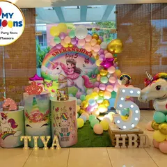 A colorful unicorn-themed fifth birthday. The setup includes a rainbow backdrop, a large unicorn foil balloon, and a 'TIYA' marquee.