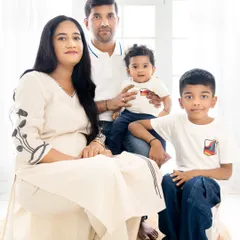 A warm and connected family portrait. The mix of sitting and standing poses adds variety, while the simple background keeps the focus on their happy faces.