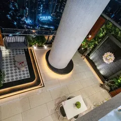 An aerial view of the terrace, showing the thoughtful layout that includes a cozy lounge area with a patterned rug and a dining spot. The integrated lighting around the pillar and seating platform creates a magical ambiance.