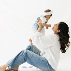 The simple joy of a mother and her baby. Dressed in casual whites and jeans, their relaxed smiles and easy connection shine in this bright, airy portrait.