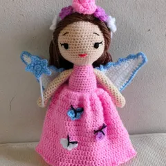 A beautiful fairy doll in a pink dress with little butterflies. She has wings and a magic wand with a star.