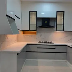 This modern kitchen features a sophisticated two-tone design with glossy white upper cabinets and sleek grey lower cabinets. The black accents on the handles and chimney create a sharp, contemporary look.
