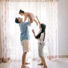 Home shoots are for being yourselves. A father lifting his daughter high in front of a bright window creates a beautiful silhouette and a moment of pure joy.