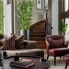 The House of Two Worlds in Gurugram is designed for balance, allowing two families to share one home while maintaining their individuality. This living area, with its warm tones and view of the helical staircase, is a shared space that feels both personal and connected.