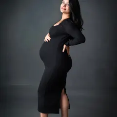 A sleek and stylish solo portrait. This mom-to-be looks incredible in a black bodycon dress and heels, showing a modern and confident side of maternity.