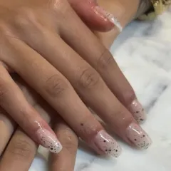 A closer view of the delicate speckled nail art on these long, clear extensions. It's a minimalist design with a touch of personality.