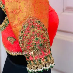 A detailed view of an embroidered sleeve cuff. This design features a 'Jharokha' window motif with an elephant, intricately crafted with zardozi and beads, and finished with a fringe of pearl tassels.