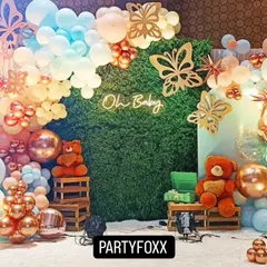 A butterfly-themed baby shower with a green hedge wall, a neon "Oh Baby" sign, and a beautiful arch of pastel and rose gold balloons.