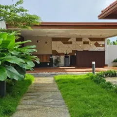 A stone pathway leads through a manicured lawn to a modern outdoor patio area. The use of low-profile lighting fixtures ensures the garden is usable and beautiful even after sunset.