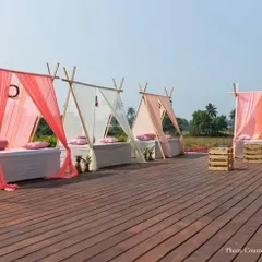 For a modern, relaxed vibe, I offer unique seating like these teepee-style cabanas. This setup on a wooden deck provides shaded, comfortable lounging spots for guests at a daytime event.