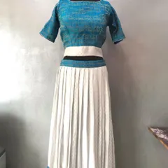 A modern take on a saree lehenga, using a simple blue and white saree. The design features a boat neck blouse and a pleated skirt with a contrasting border.