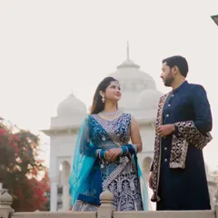 The couple stands on a balcony overlooking the heritage site, sharing a candid moment. This image captures a natural interaction, with the beautiful architecture providing a stunning backdrop for their pre-wedding shoot.