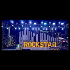 A panoramic view of the epic Rockstar stage at night, complete with a drum kit, giant guitar prop, and professional lighting rig.