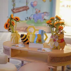 A cozy seating area with a hand-painted backdrop of Pooh and his friends, complete with themed furniture and honey pot details.