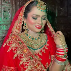 A classic red bridal look is always a winner. Here, I've paired a vibrant red lip with gold and green jewelry, creating a timeless and royal appearance for her special day.
