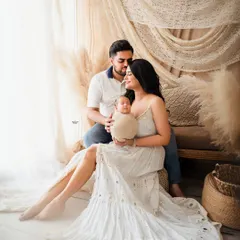 Welcoming their newborn in the coziest setting. This beautiful family portrait captures the new parents adoring their baby, surrounded by the soft textures of our boho studio.