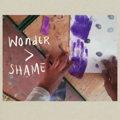 Wonder is a powerful tool for learning that we encourage over any feeling of shame. Here, a child's painted handprint symbolizes the freedom to make a mess, experiment, and learn through hands-on, sensory experiences without fear of getting it wrong.