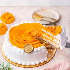 A slice is lifted from our Mango Fresh Cream Cake. You can see the layers of light vanilla sponge, fresh cream, and our homemade aamras packed with diced mangoes.