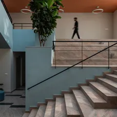The interior of the Nirbhaya Centre is organized around a central, light-filled atrium with a grand staircase, designed to be an uplifting and non-intimidating space.