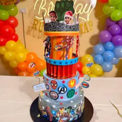 An action-packed, four-tier Avengers carousel cake. This custom design features a moving top layer and photos of the birthday boys, making it a truly interactive and personalized superhero experience.