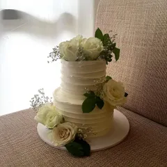 A classic and romantic two-tiered engagement cake. This 1.5kg chocolate cake has a rustic textured buttercream finish and is adorned with fresh white roses and baby's breath.