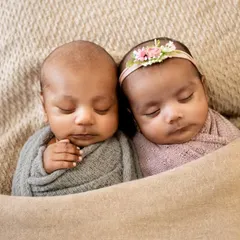 Two little babies, sleeping side-by-side. This simple, classic shot focuses on the twins themselves, wrapped in soft, complementary colors to highlight their connection.