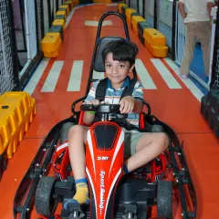 Future racer in training! A young driver gets ready for his lap on our indoor go-kart track. The track is designed for safety and fun, making it a highlight for any birthday party or day out.