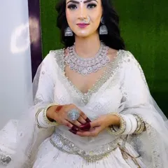 Another pose from the bride in the white lehenga, highlighting the sparkle of the AD necklace and maang tikka against the elegant outfit.