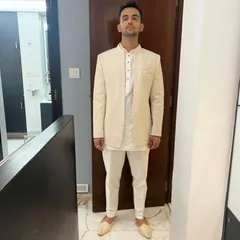This is a cream Lakhnavi open Jodhpuri jacket with a chevron pattern, worn over a simple cream kurta and pant. It's a sophisticated choice for an engagement or Roka ceremony.