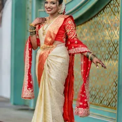 A full-length view of this stunning Telugu bride shows how the pre-pleated drape creates a slimming and elegant silhouette. The off-white and red silk saree is styled with a traditional embroidered dupatta for a complete bridal look.