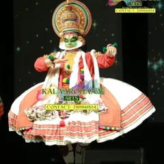 A Kathakali performer captured mid-dance on a darkened stage. The dramatic lighting highlights the artist's expressive face and the grandeur of the costume, creating a powerful theatrical moment.