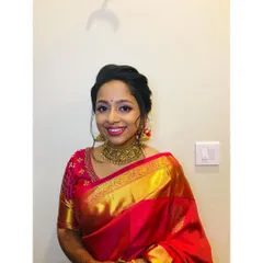 This bride is absolutely slaying her reception look in a vibrant red and gold silk saree. The makeup is elegant and classic, with a smile that shows how happy she is.