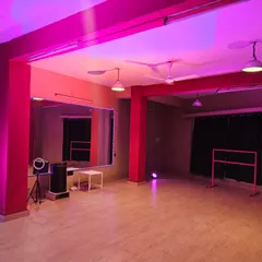 See the studio in a vibrant pink glow. This view showcases the full-length mirrors, essential for checking form during dance or fitness practice, alongside the portable ballet barre and content creation equipment.