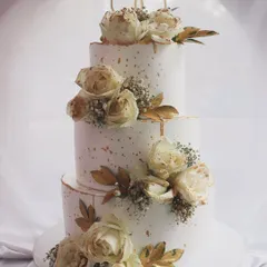 A classic and romantic three-tier wedding cake. I adorned this beauty with cascading off-white roses, baby's breath, and a touch of gold leaf for an elegant and timeless look.