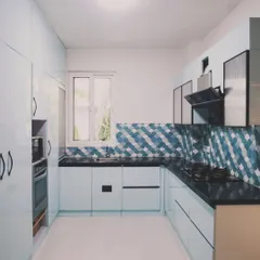 This U-shaped kitchen makes a statement with its vibrant, fish-scale patterned backsplash in shades of blue and green. We paired it with light blue cabinetry and a black granite countertop to create a space that is both playful and highly functional, proving that practical kitchens can also be full of personality.