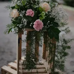 A rustic yet elegant floral piece. This arrangement of pink carnations, pale roses, and cascading greenery on a wooden crate is perfect for adding a touch of charm to event entrances or corners.