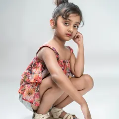 This kids' portrait captures a moment of quiet thought. The simple pose and clean background highlight her natural expression, showing that kids' photos can be both stylish and authentic.