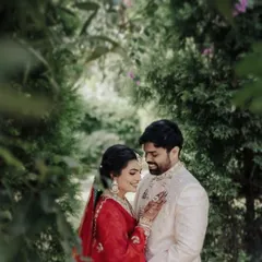 A romantic portrait of the couple nestled in a lush garden. The framing with the leaves adds a sense of intimacy, creating a private, enchanting world just for them.