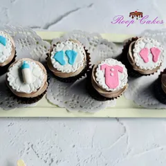 Classic baby shower cupcakes featuring handmade fondant toppers. This set includes adorable baby footprints, a milk bottle, and a little onesie, perfect for celebrating the upcoming arrival.
